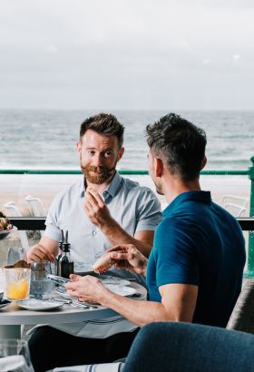 A couple enjoying a seafood meal at the Oyster Box looking out onto St. Brelade