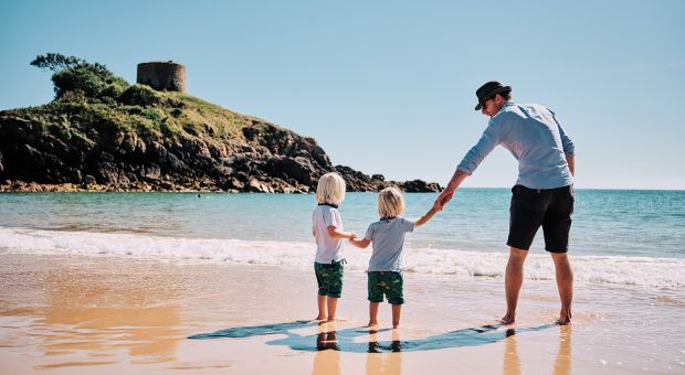 father and children on the beach at Portelet.