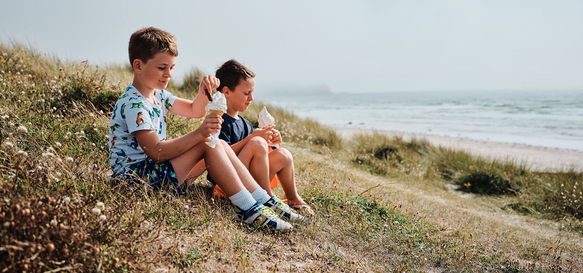 Enfants assis dans les dunes dégustant une glace