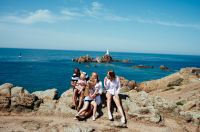 Family eating ice cream by the sea with a view of a lighthouse