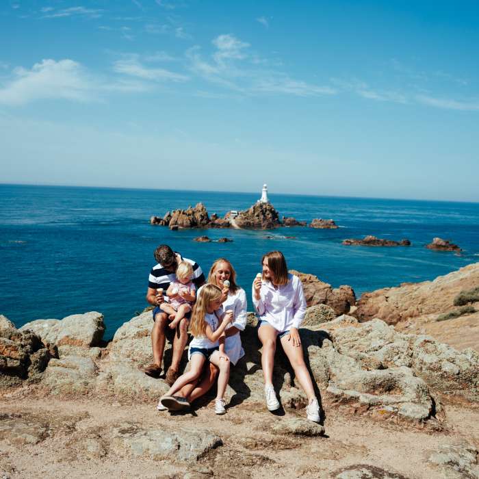 Family eating ice cream by the sea with a view of a lighthouse