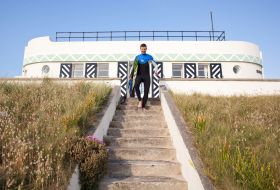 Surfer makes way down private steps to beach from Barge Aground