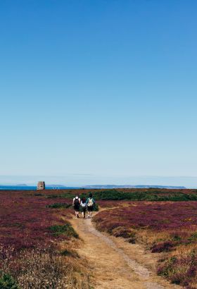 Three people walking along the headland in St. Ouen