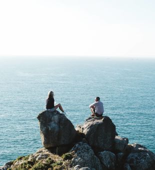 A couple sitting on a rock over looking the sea on the north coast cliffs