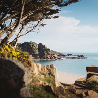 Bench overlooking a golden, sandy bay and dramatic headland