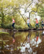 Family hoping over stepping stones in a stream at St. Catherine