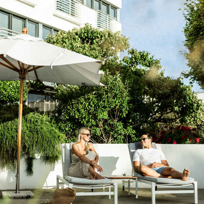 Young couple laying on sun loungers at The Atlantic Hotel, Jersey