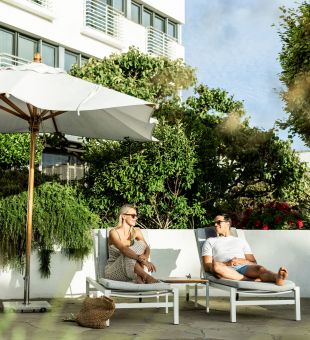 Young couple laying on sun loungers at The Atlantic Hotel, Jersey