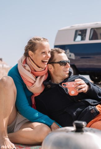 Couple drinking tea near their campervan on the slipway at the beach