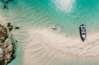 Arial shot of Les Minquiers, Jersey, with turquoise waters, a boat and paddle board
