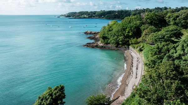 Aerial shot of swimmers entering the turquoise sea at Bel Val Bay in Jersey.