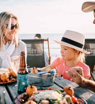Couple with young child enjoying al fresco dining in the sun overlooking the sea