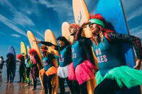 surfers holding surfboards dressed in 80s themed outfits