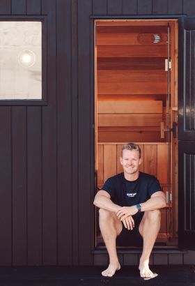 Young man sitting on the stairs of a sauna