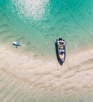 Aerial shot of a boat and paddle boarder from above. Minquiers, Jersey