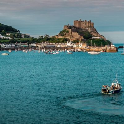 Fishing boat on the water in front of a medieval castle in Gorey, Jersey