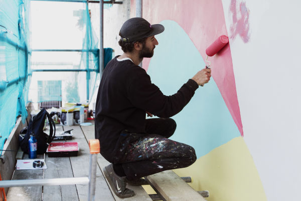 The artist Bokra painting a mural in St. Helier