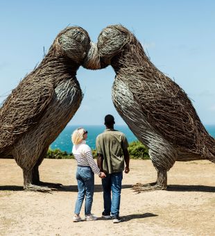Young couple admiring the puffin sculptures at Plemont, Jersey