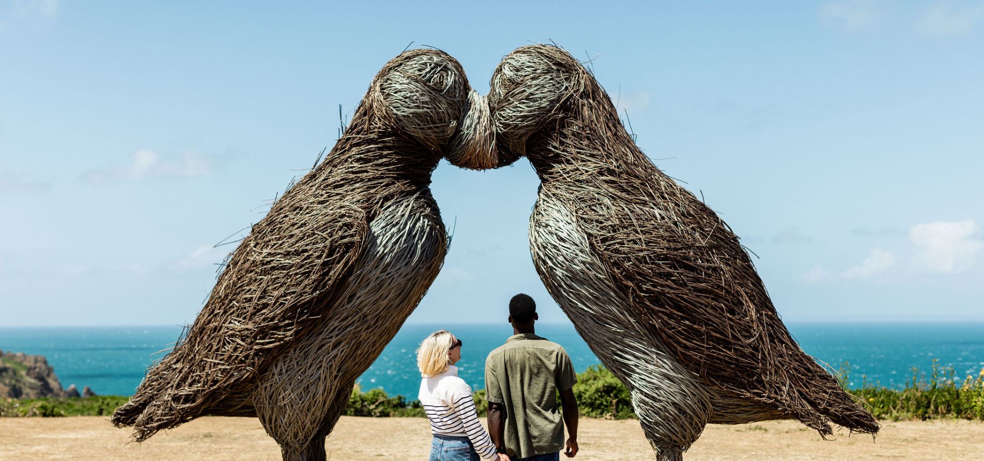 Young couple admiring the puffin sculptures at Plemont, Jersey