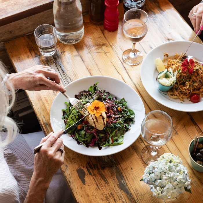 Two women eating a salad and crab linguini at Portelet Bay Cafe, Jersey
