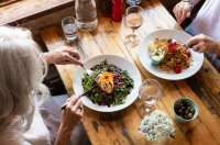 Two women eating a salad and crab linguini at Portelet Bay Cafe, Jersey