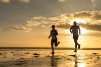 two people running on the beach at sunset