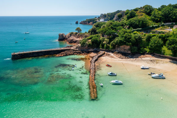 Aerial view of clear turquoise sea with boats moored in harbour at St. Brelade