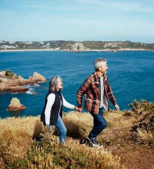 A couple walking on a coastal headland in autumnal clothing