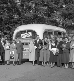 Group of couples standing in front of a vintage bus